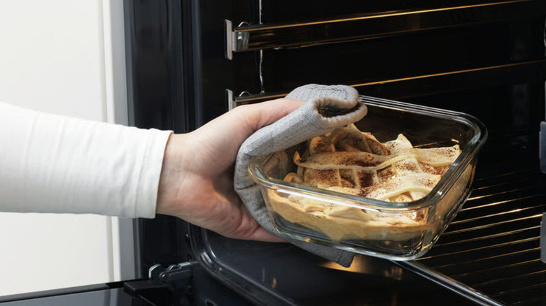 Person putting a IKEA 365+ glass food container into an oven