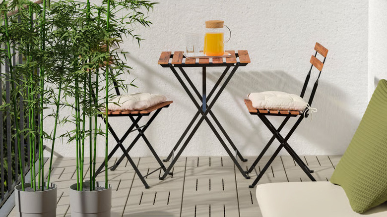 A cafe table and chairs sits on a patio covered in light gray RUNNEN decking tiles