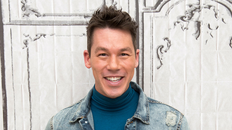 David Bromstad smiling in front of a white fabric background.