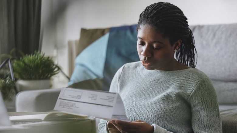 a woman sitting on the floor reading her electric bill