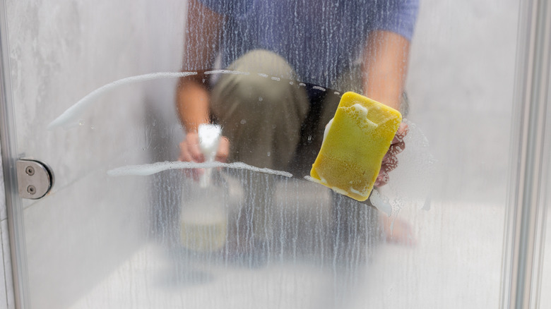 Woman using sponge on shower door