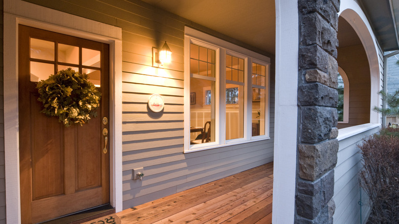 Porch light on in a cozy porch with wreath on the door