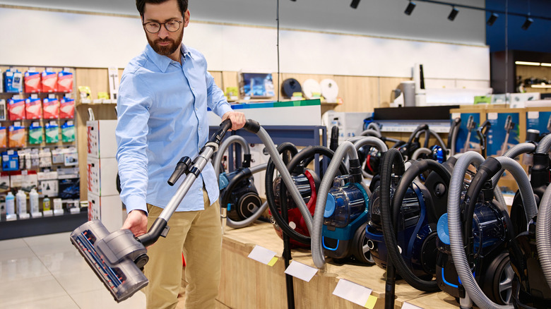 Man examining vacuum cleaner in store