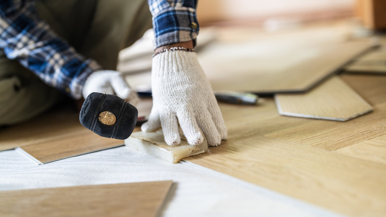 person installing planked flooring into their home