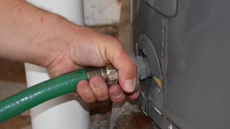 Hand attaching hose to water heater