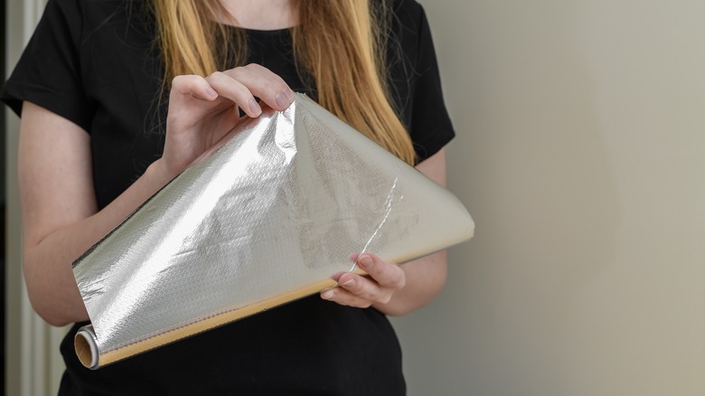 person unrolling aluminum foil