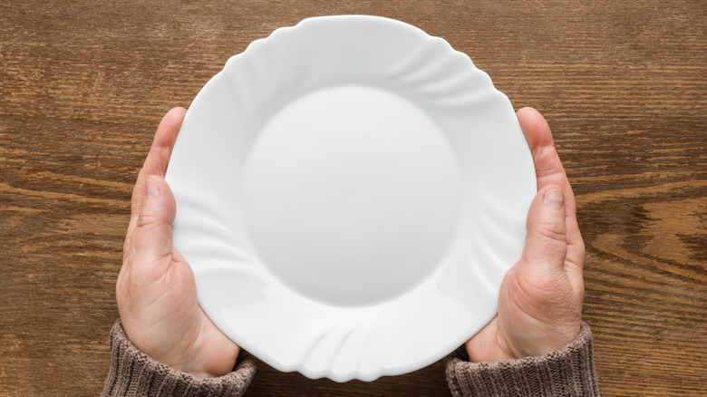 Hands holding white plate