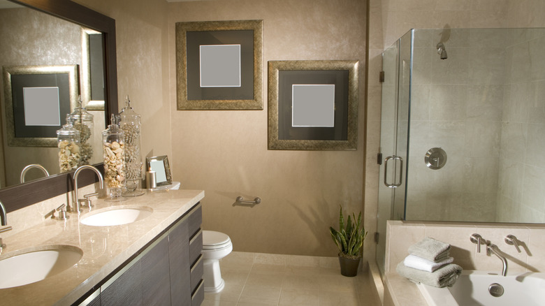 Spa-like bathroom with double sinks, glass shower doors, and a tub