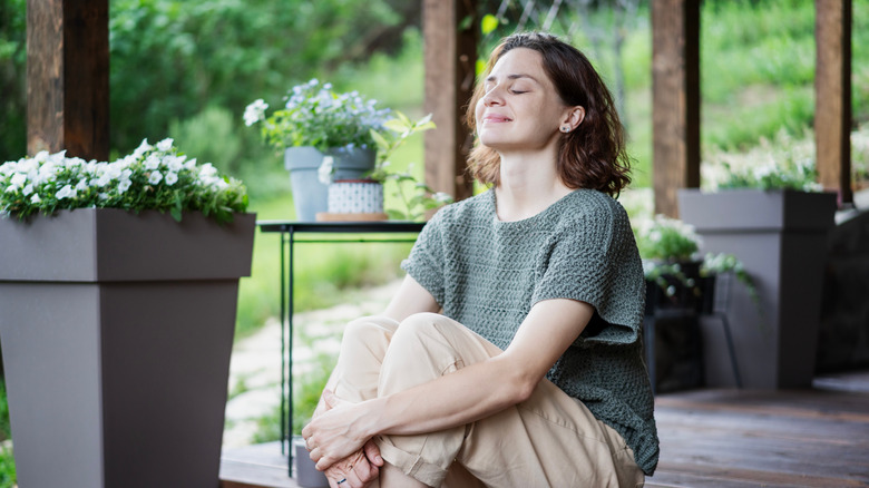 Woman sitting on the porch deck with planters around