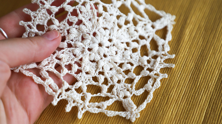Close-up of a hand holding a small lace doily