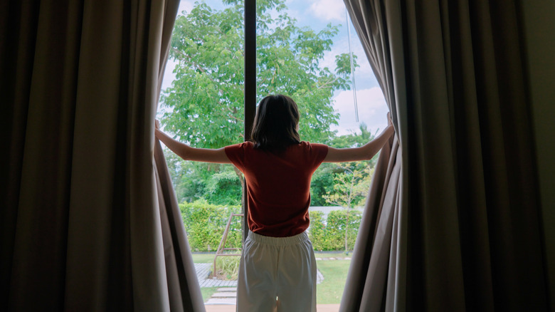 Woman open curtains on glass doors