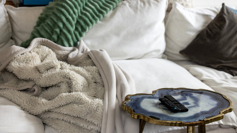 A white couch with a couple of throws draped over it.