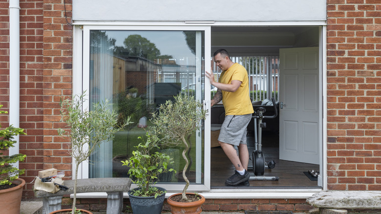 Man pushing aside a sliding glass door in his home