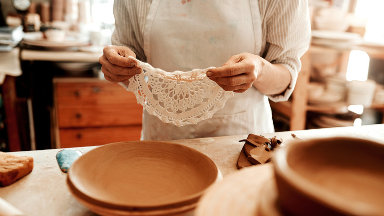 Person holding a doily near a counter with trays on it