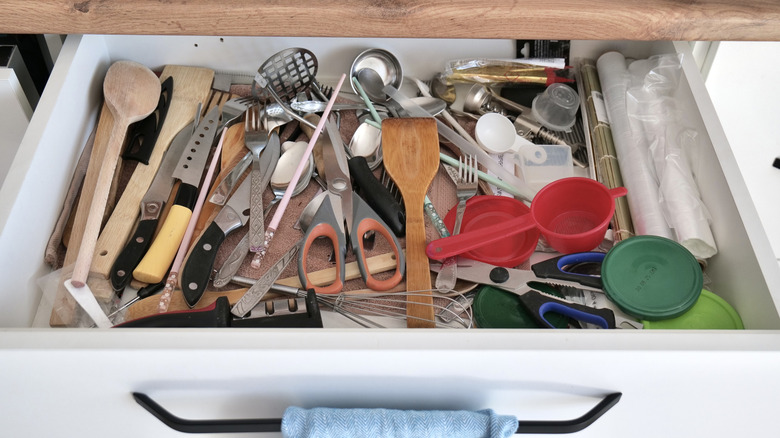 A messy kitchen drawer full of loose utensils.