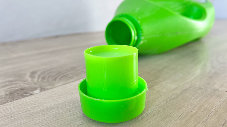 A laundry detergent bottle cap, with the bottle in the background