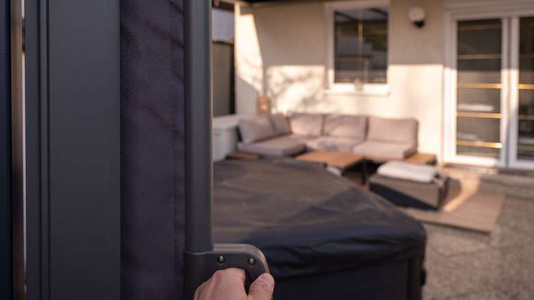 A person pulls on a privacy screen covering a patio