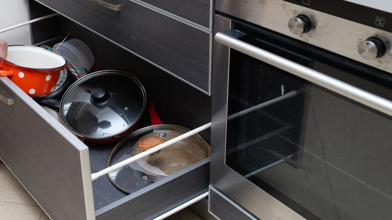 Cluttered cabinet drawer with loose pot lids