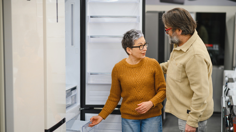 A couple and a saleswoman shopping for a refrigerator in a store