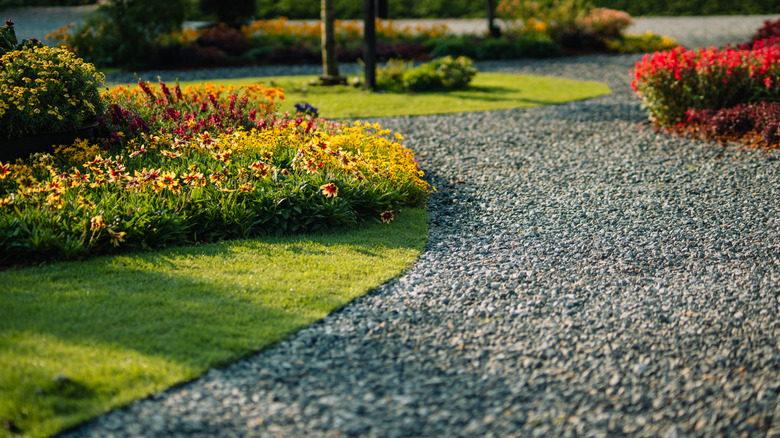 Curved gravel driveway with plants and flowers on one side