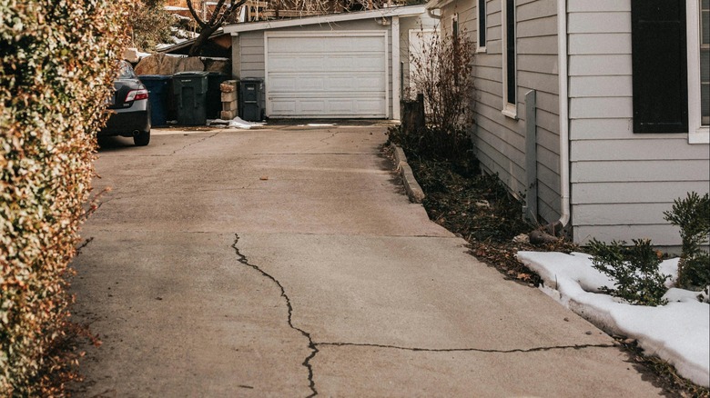 Driveway with large cracks next to house and in front of garage
