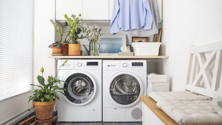 A small laundry area with shirts hanging from a wall or ceiling mounted hanger