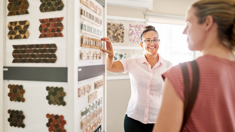 A person discussing tile choices with a salesperson in a store