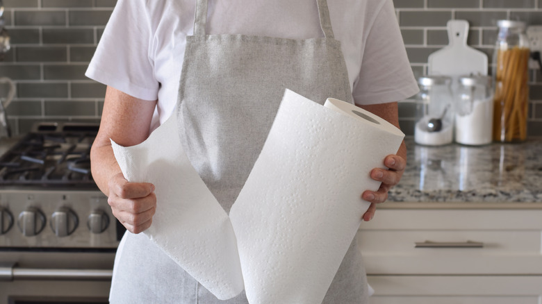 A person tearing a paper towel sheet in a kitchen