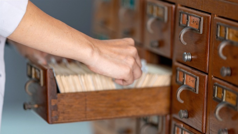Person looking through old library card catalog