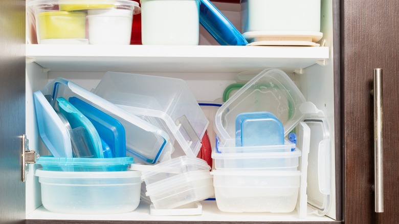 Kitchen cabinet cluttered with plastic storage containers