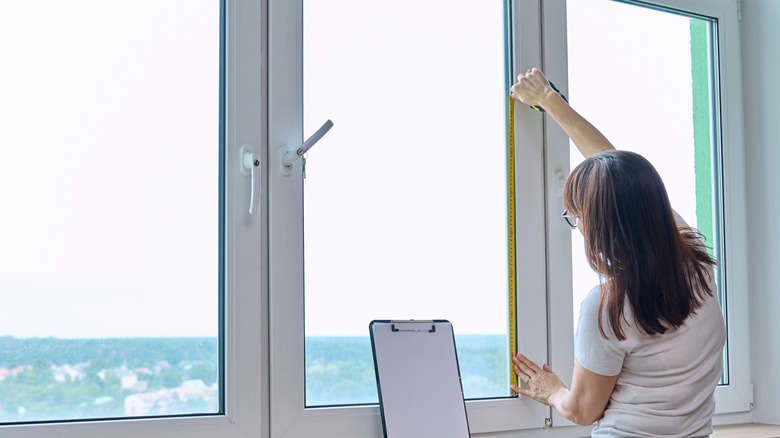 A person measuring a window