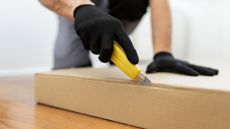 a person cutting cardboard with a box cutter