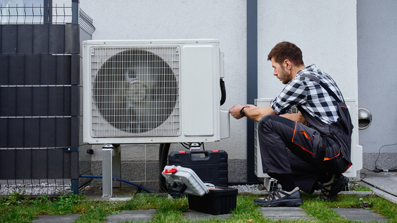 Technician performing maintenance on HVAC on building exterior
