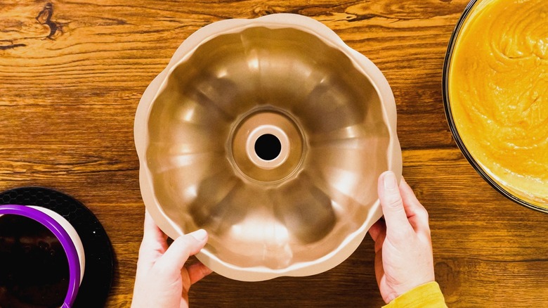 Person putting a Bundt pan down on a wooden countertop