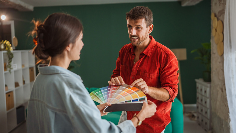 A couple is discussing the paint for their living room while holding swatches