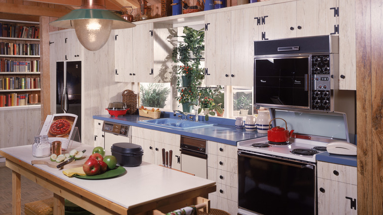 A 1980s kitchen with white cabinets and lots of natural wood