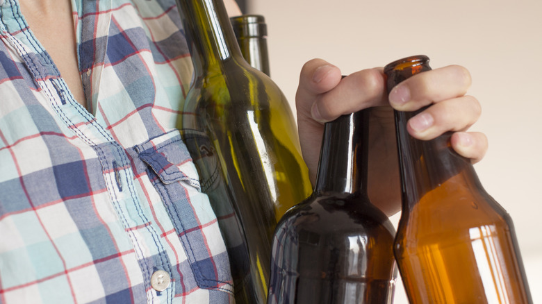 person holding several empty wine bottles