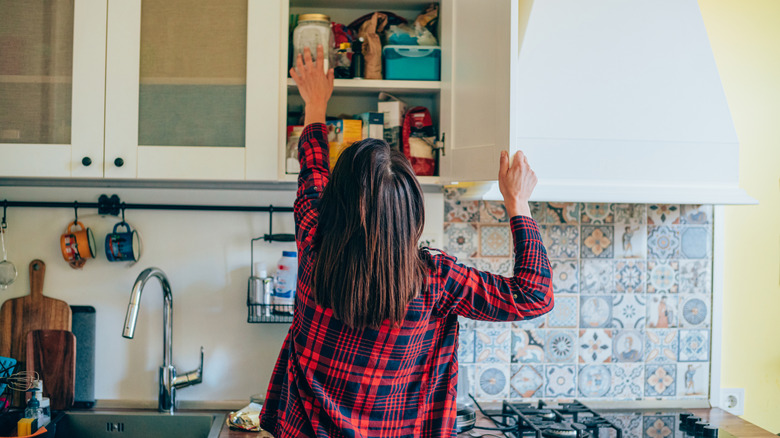 Woman reaching into kitchen cupboards