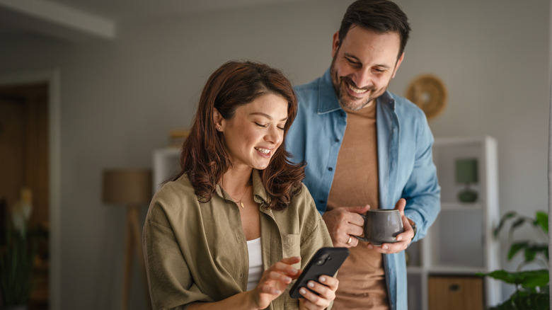 A couple smiles while scrolling on a phone