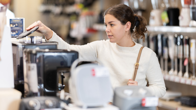 A woman looking at kitchen appliances in a store.