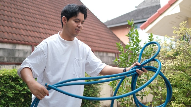 Man trying to clean up a tangled garden hose