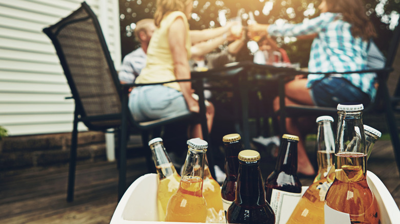A closeup of drinks in cooler with patio party in the background