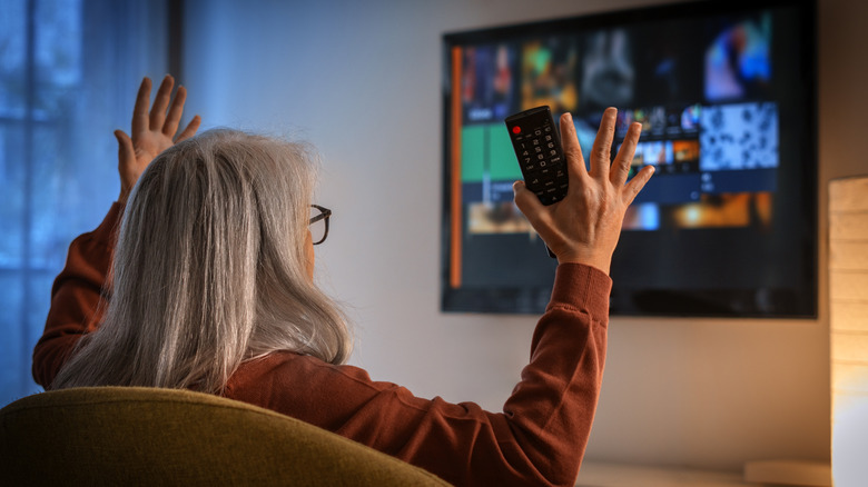 Woman with a remote control sitting in front of a smart TV