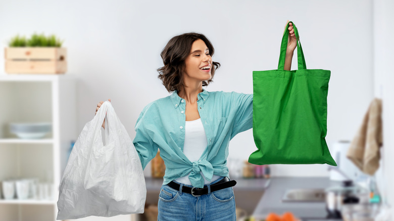 Woman holding shopping bags while smiling in her home