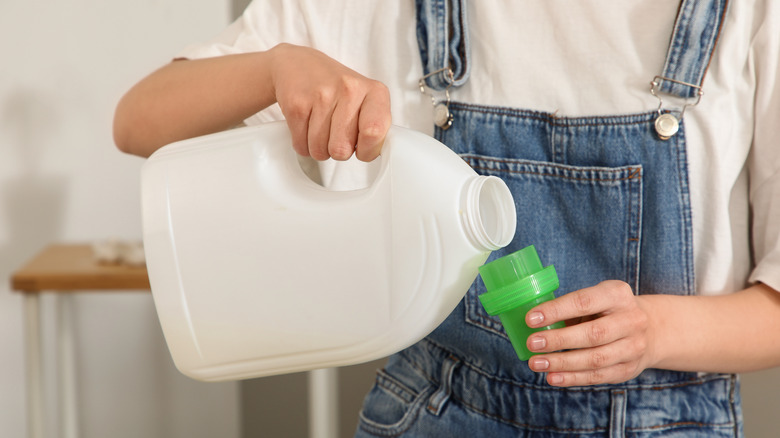 hands pouring laundry detergent