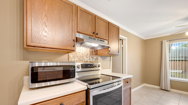 A dated kitchen has honey oak cabinets