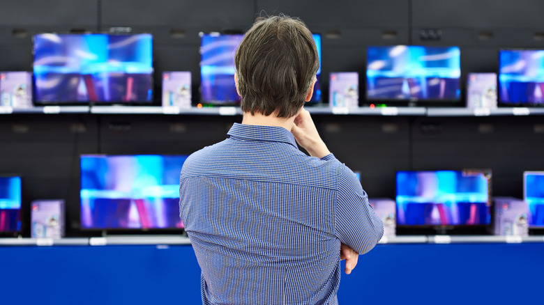 Man considering a selection of TVs in a store display