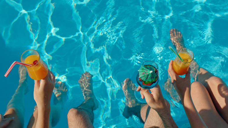 An aerial view of people holding their drinks with their legs in pool