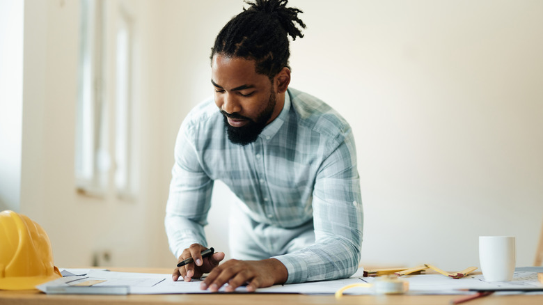 Person planning a DIY project with a blank wall behind him