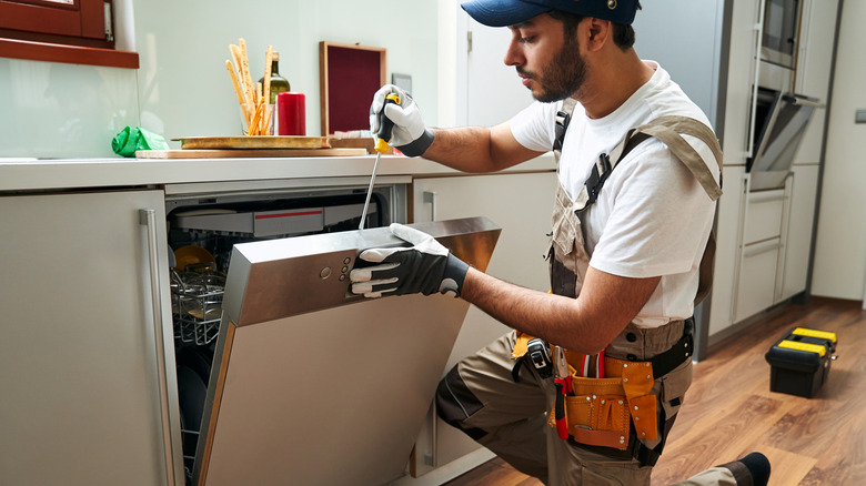 A handyman doing maintenance on a dishwasher